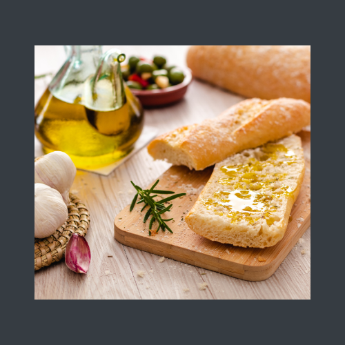 Ein knackiges Baguette mit Olivenöl-nativ. Im Hintergrund steht das Olivenöl in seiner goldenen Farbe.